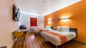 Habitación de hotel con dos camas, un escritorio, una silla, un televisor y una ventana con cortinas rojas.