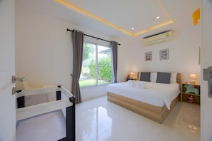 Habitación de hotel con cama, ventana con cortinas, mesita de noche con lámpara y aire acondicionado instalado en la pared.
