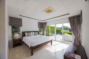 Un dormitorio moderno con una cama grande, una mesita de noche, un escritorio y vistas al exterior.