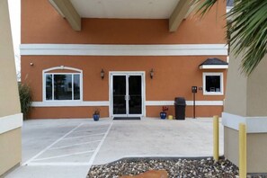 Entrada de un edificio con estacionamiento, puertas dobles y macetas.