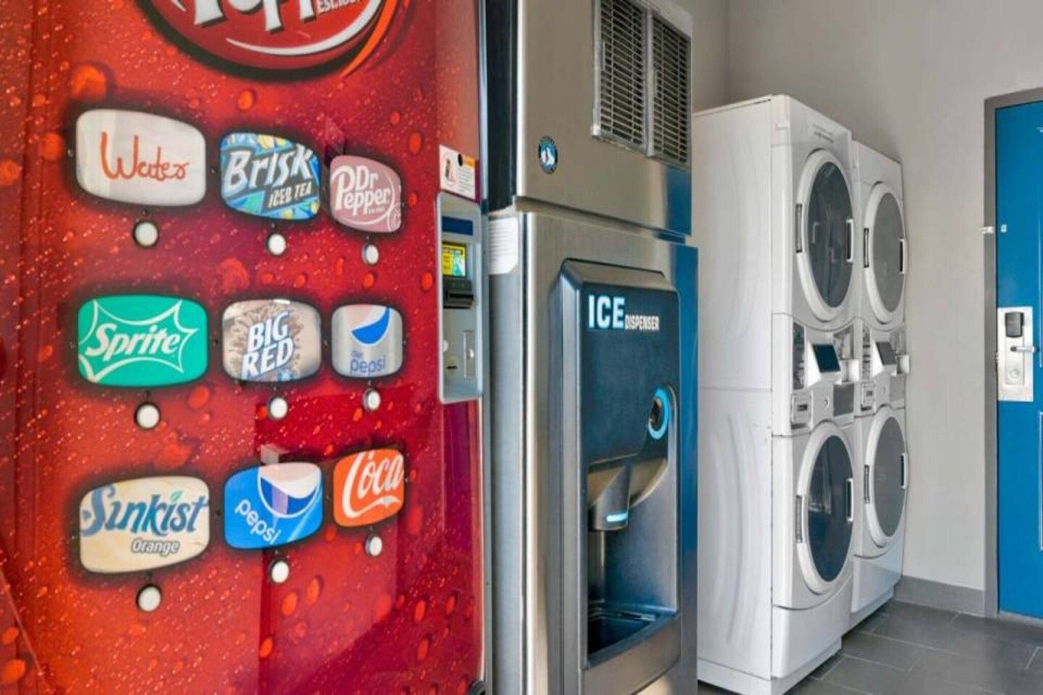 Una lavandería con máquina expendedora que ofrece diversas bebidas y una fila de lavadoras.