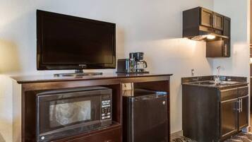 Una kitchenette compacta equipada con microondas, refrigerador, cafetera y un televisor de pantalla plana.