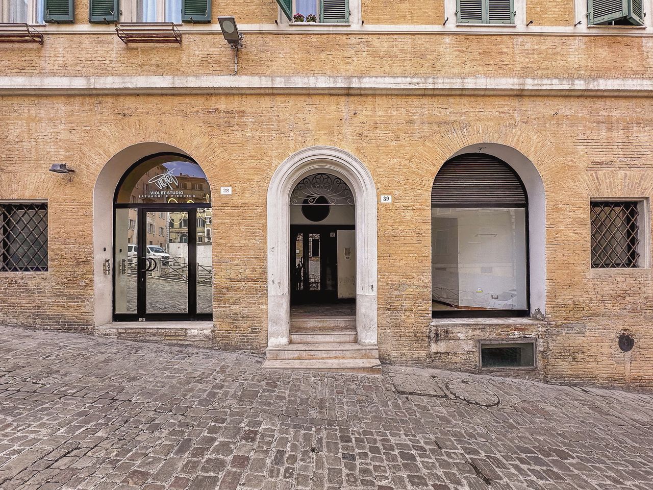 Une façade d’immeuble ornée de trois portes cintrées, numérotées 38, 39 et 40, qui donnent accès à des espaces intérieurs.