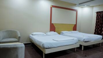 A hotel room with two single beds, a chair, and a ceiling fan.