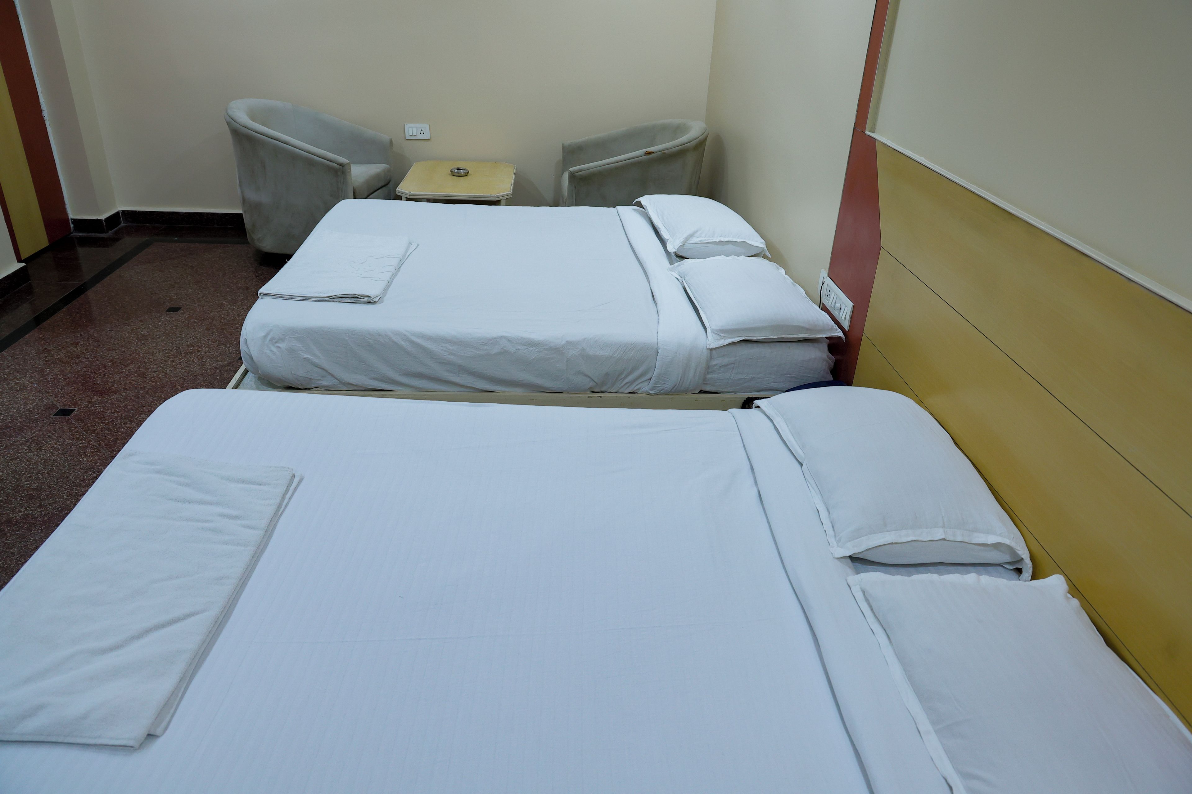 A hotel room with two beds, a small table, and two chairs.