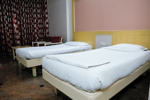 A hotel room with two single beds, a small table, and a chair. - Hotel Raj Classic Inn (Secunderabad)
