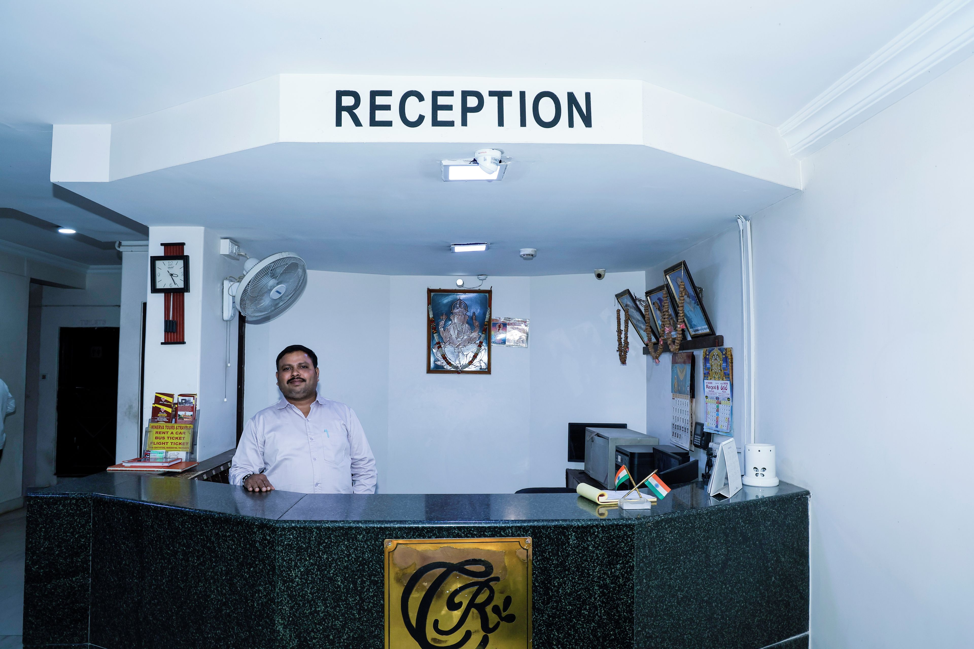 A reception desk with a sign above it, a clock, and a framed picture on the wall.