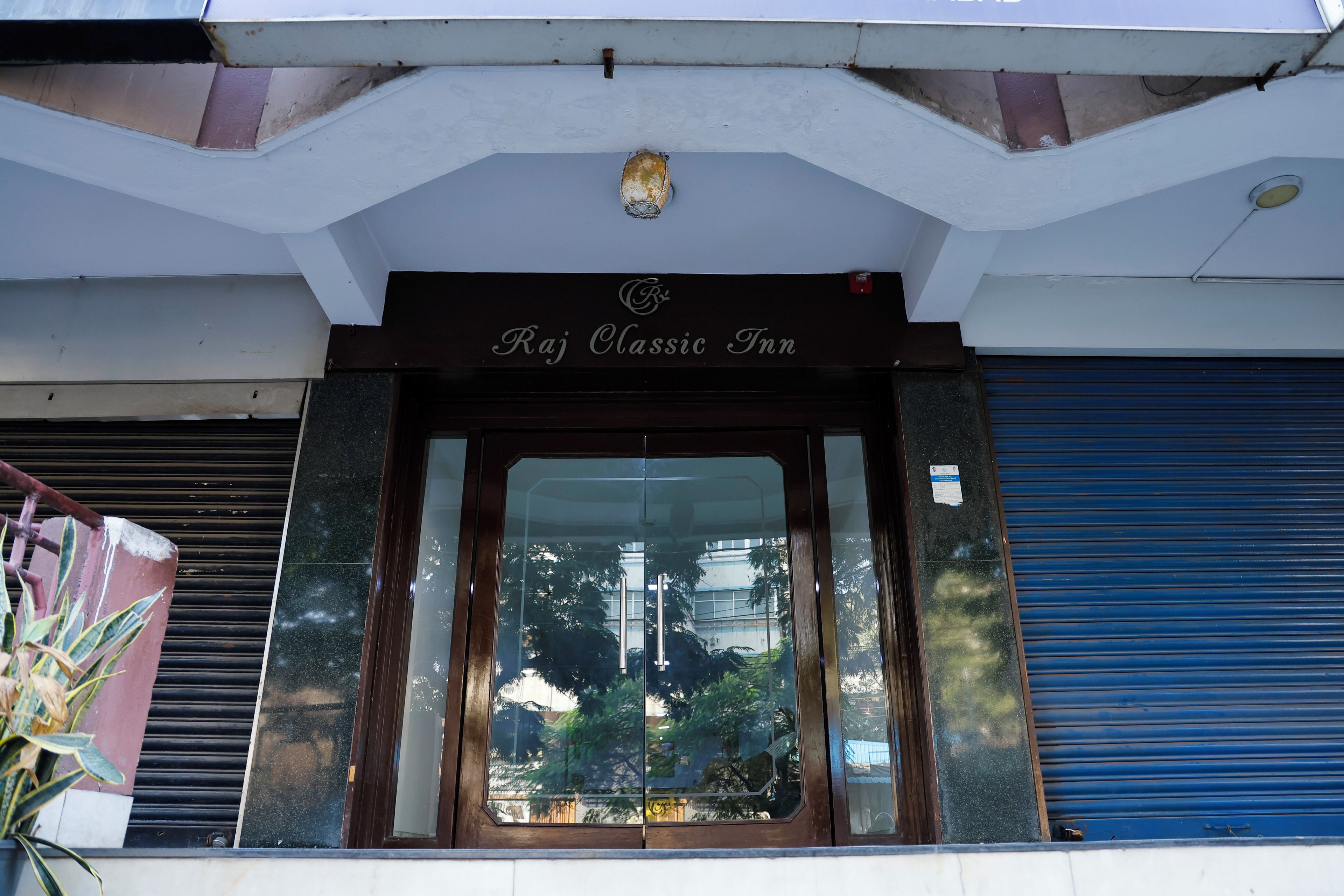 The entrance to Raj Classic Inn with a clear view of the surrounding area through the glass doors.