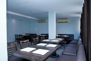 A restaurant with multiple tables and chairs, air conditioning units, and a high ceiling. - Hotel Raj Classic Inn (Secunderabad)