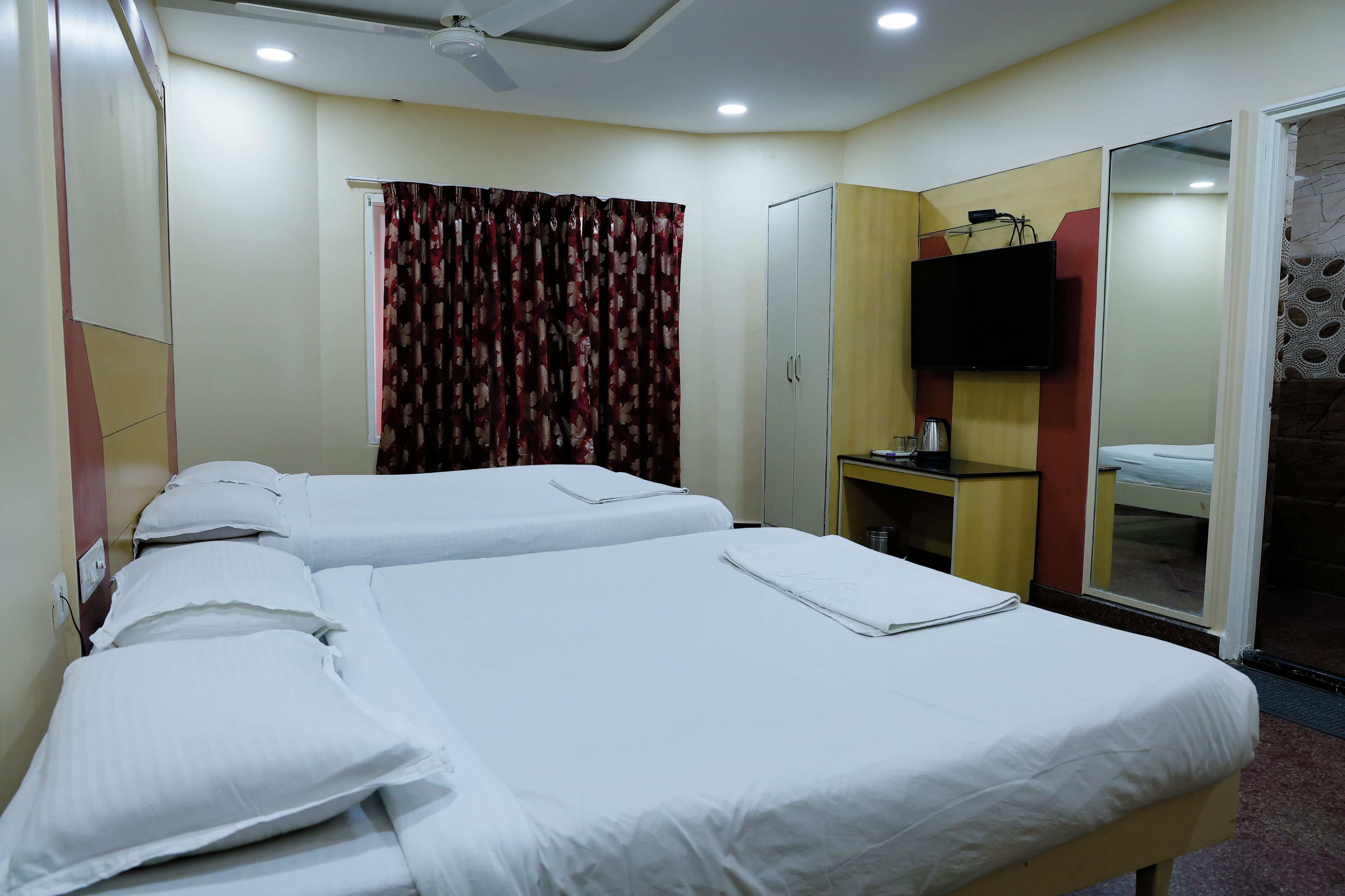 Une chambre d’hôtel avec deux lits, une télévision, un bureau et une armoire.