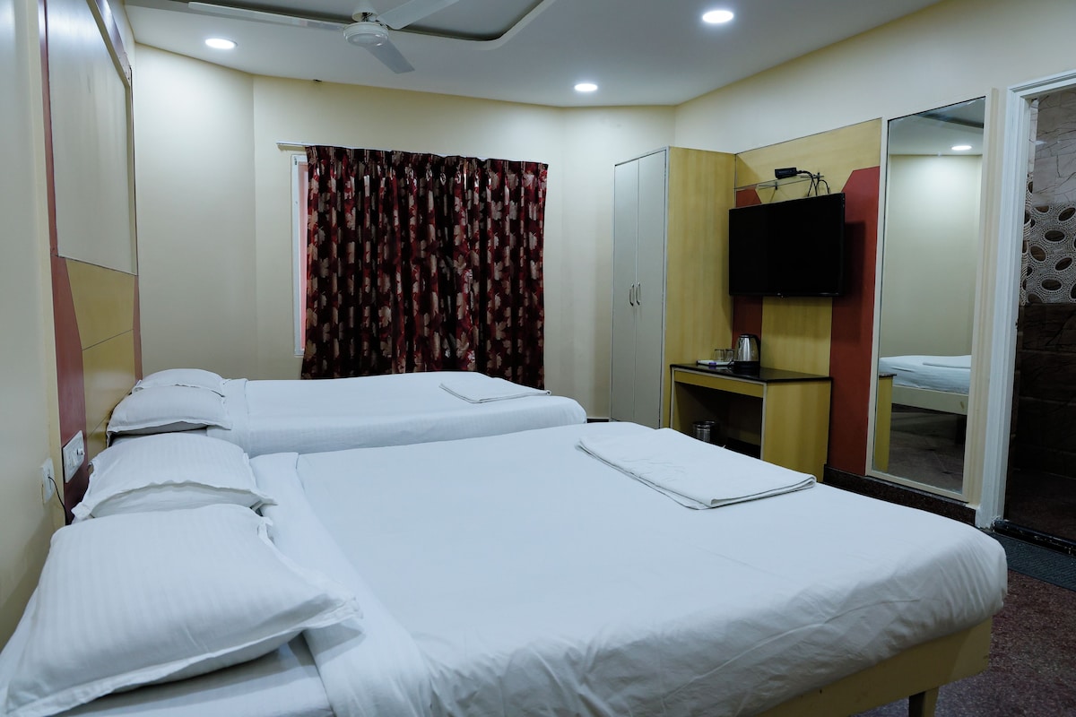 A hotel room with two beds, a television, a desk, and a wardrobe.
