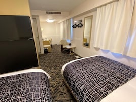 Habitación de hotel con dos camas, un escritorio, una silla y un espejo.