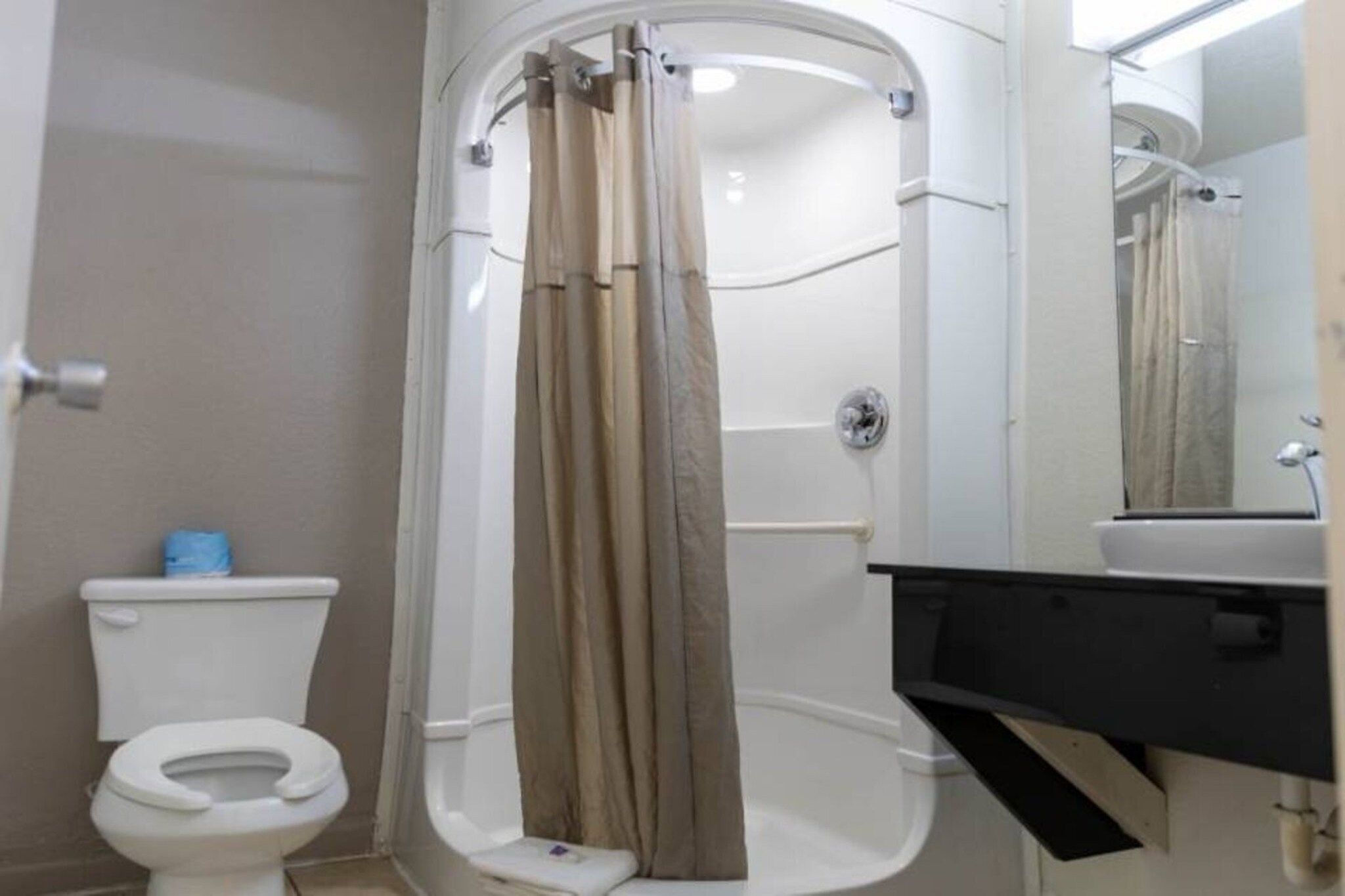 A bathroom with a toilet, a shower enclosure, and a sink.