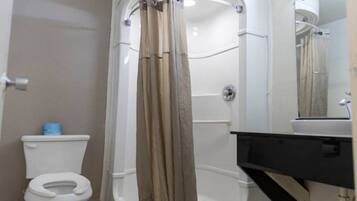 A bathroom with a toilet, a shower enclosure, and a sink.