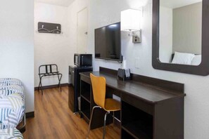 Une chambre d’hôtel comprenant un lit, un bureau avec une chaise, une télévision et un miroir.