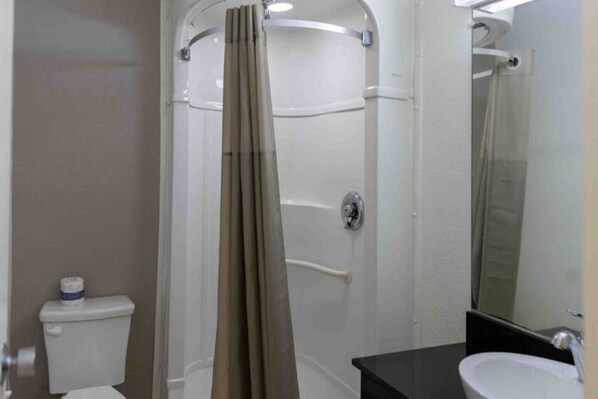 Een badkamer met douche, toilet en wastafel.