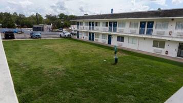 A motel with a grassy courtyard, a parking lot, and a building with multiple rooms.