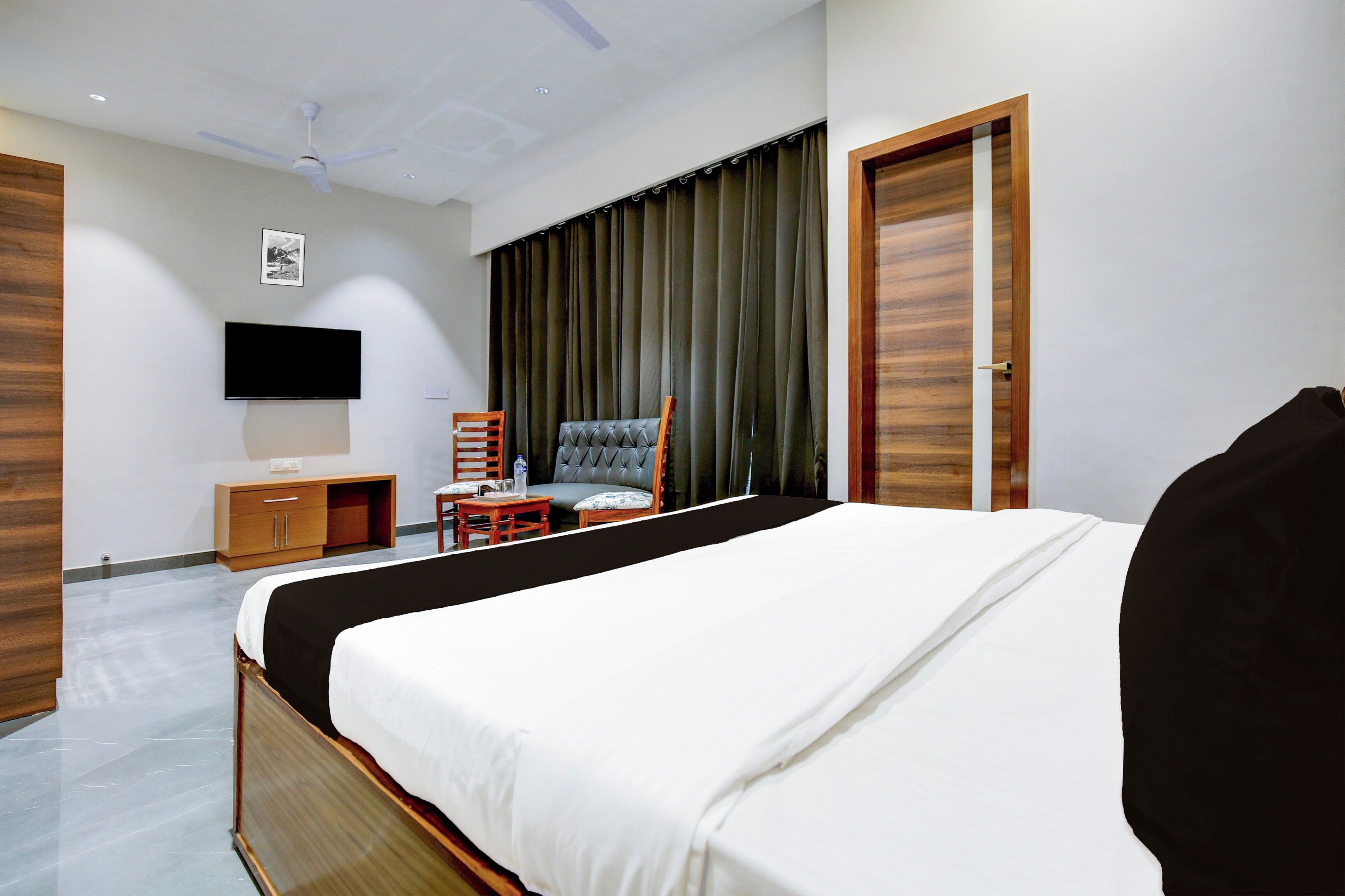 A hotel room with a bed, a TV, a chair, a desk, and a wardrobe.