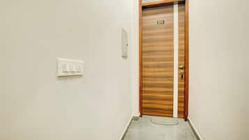 A hallway with a wooden door marked with the number 203, a light switch, and a small rug on the floor.