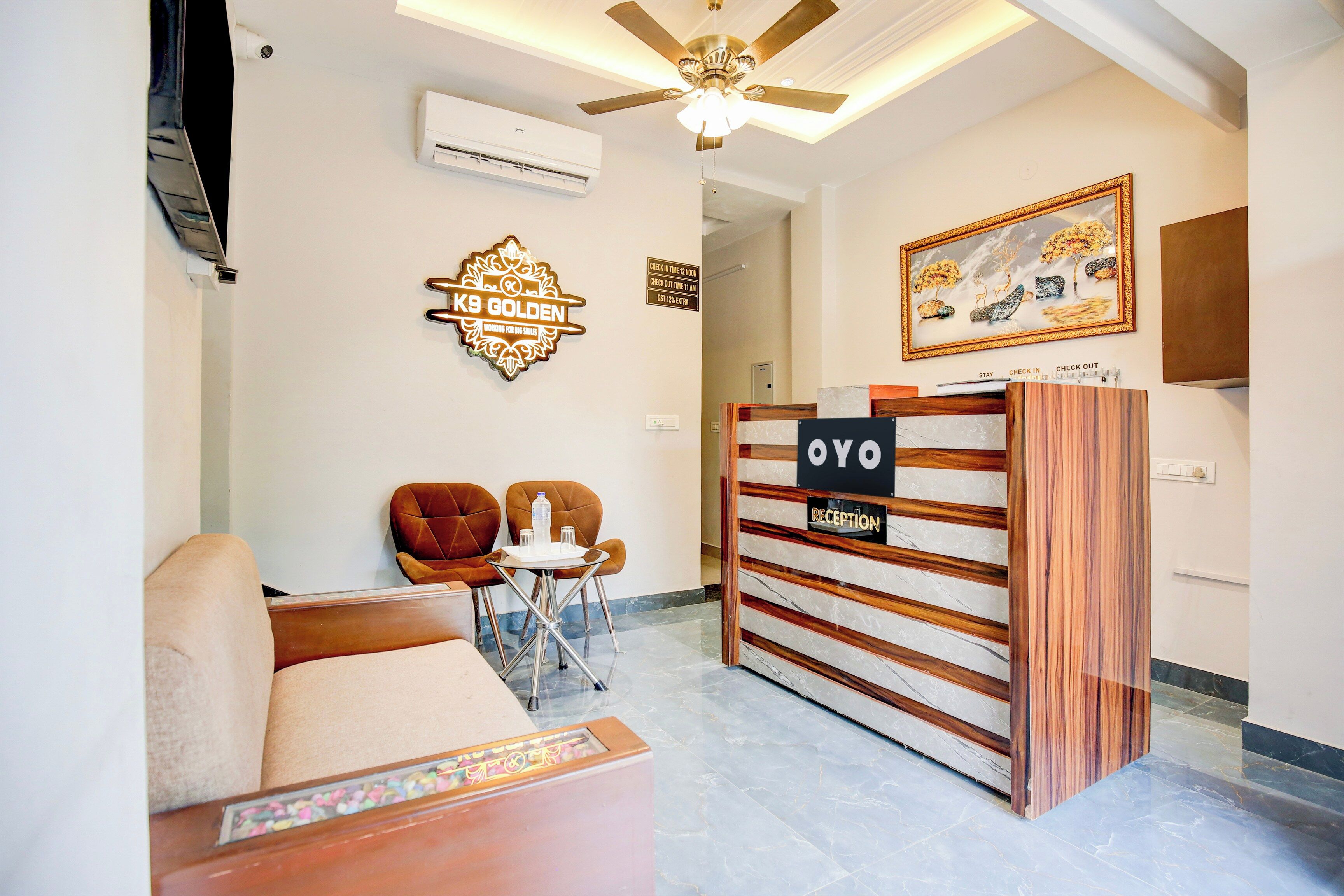 A reception area with a reception desk, a ceiling fan, a framed artwork, and a seating area with a sofa and chairs.