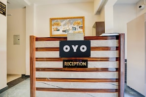 A reception desk with a sign that reads 'OYO RECEPTION' and a framed artwork above it.