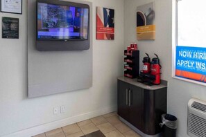 Un espace d’accueil équipé d’un téléviseur mural, d’une machine à café et d’une poubelle.