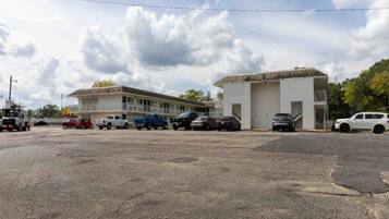A parking lot with several cars and a building with a flat roof and a single-story structure.