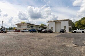 Un parking avec plusieurs voitures et un bâtiment doté d’un toit plat et d’une seule étage.