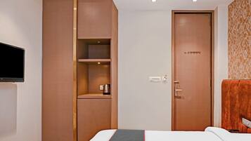 A hotel room with a bed, a wardrobe, a television, and a door.