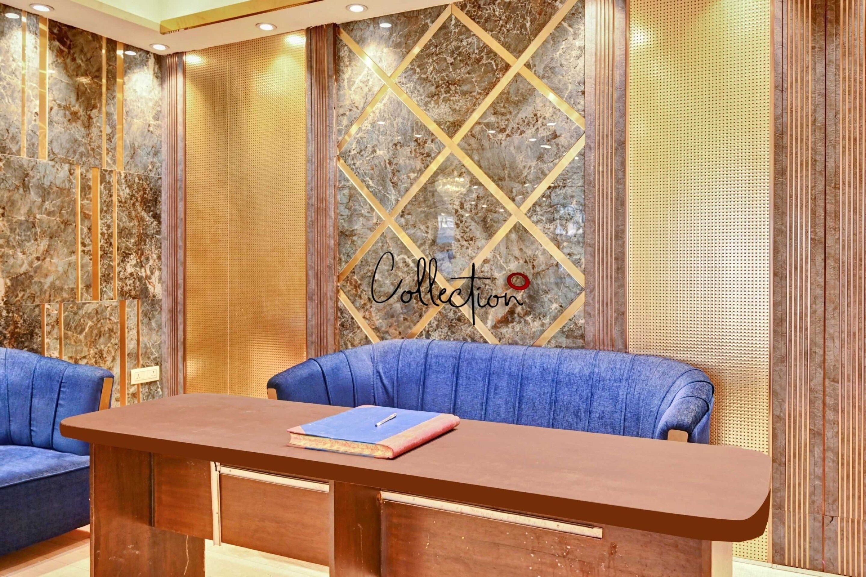 A modern interior with a blue sofa, a wooden desk, and a wall with a geometric pattern and the word 'Collection'.