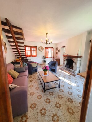 Ein Wohnzimmer mit Treppe, Kamin und Couchtisch mit Blumen.