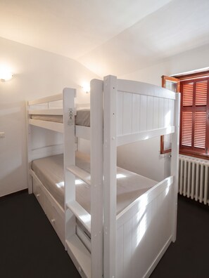 Ein Etagenbett mit Holz Kopfteil und weißer Matratze.