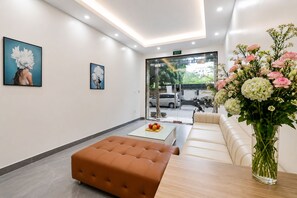 A modern lobby with a seating area, a coffee table with fruit, and a vase of flowers. - 8 Nguyen Van Ngoc (BA DINH)