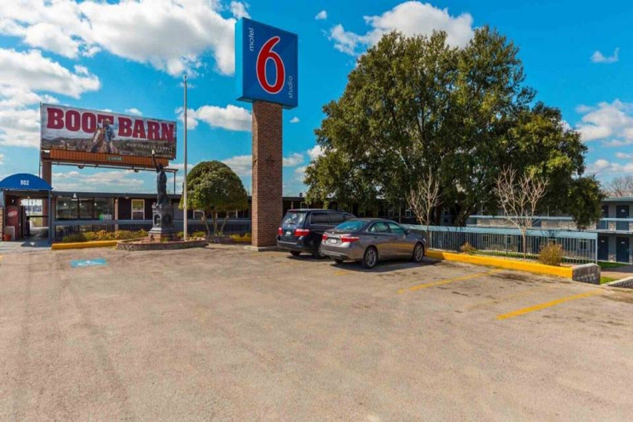 Un motel appelé « Boot Barn », avec une grande enseigne bleue, un parking et quelques voitures garées.