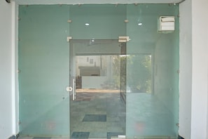 A glass door with a metal handle and a small rectangular window on the upper right. - Hotel O S Town Guest House (Ludhiana)