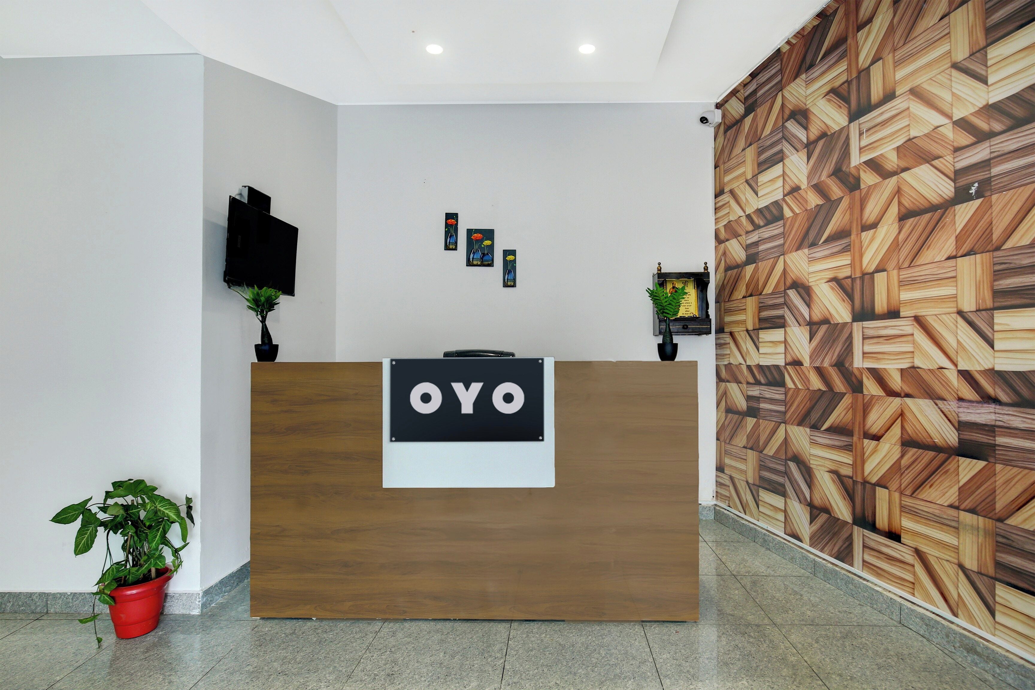 Un comptoir d’accueil avec une enseigne indiquant « OYO » et un mur décoré d’un motif se trouve à droite.