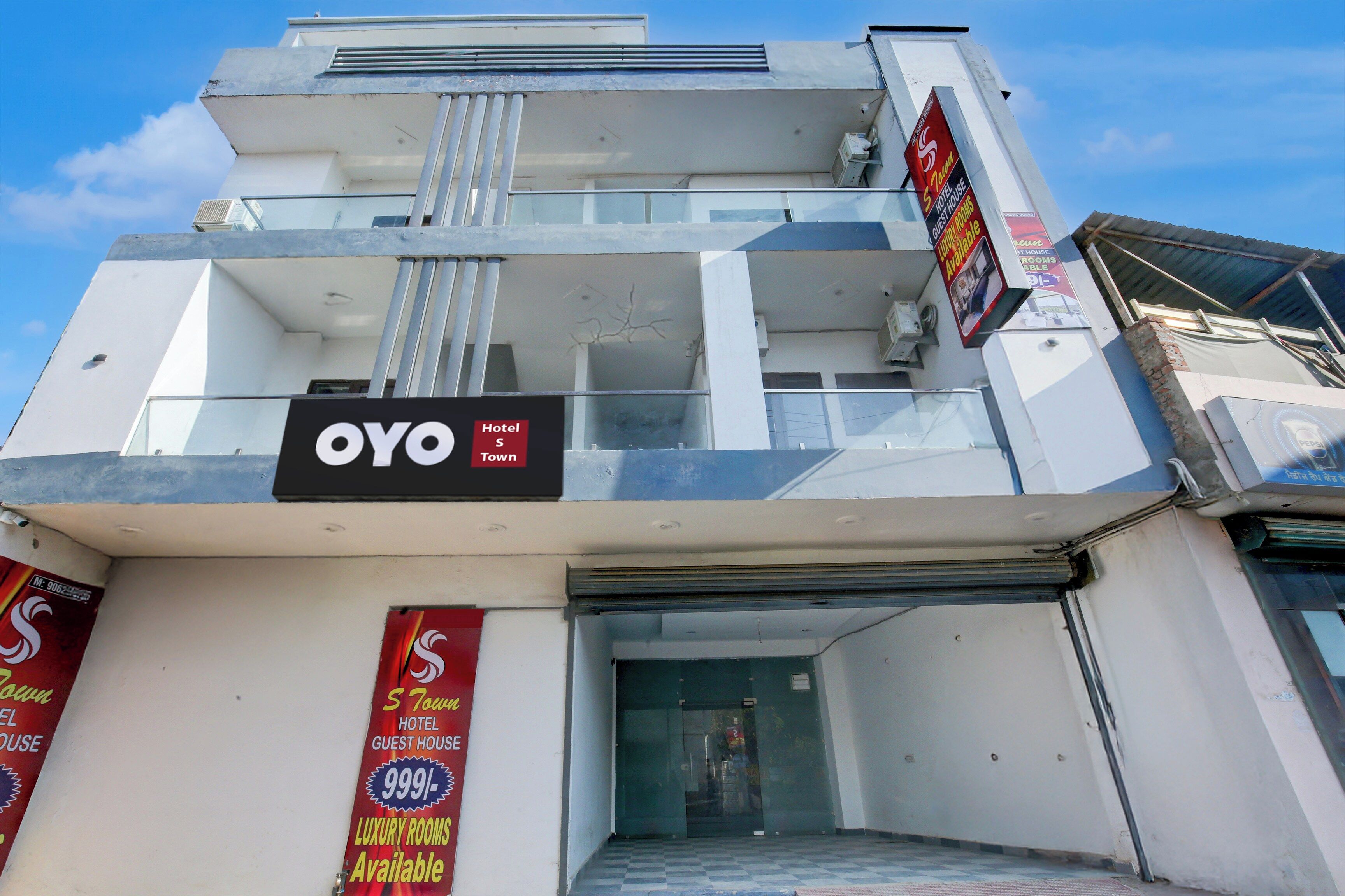 A hotel with a sign indicating 'OYO Town Hotel' and 'Luxury Rooms Available'.