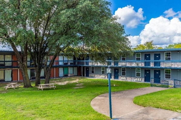 Un edificio de varios pisos con un patio central, un árbol y una mesa de picnic.