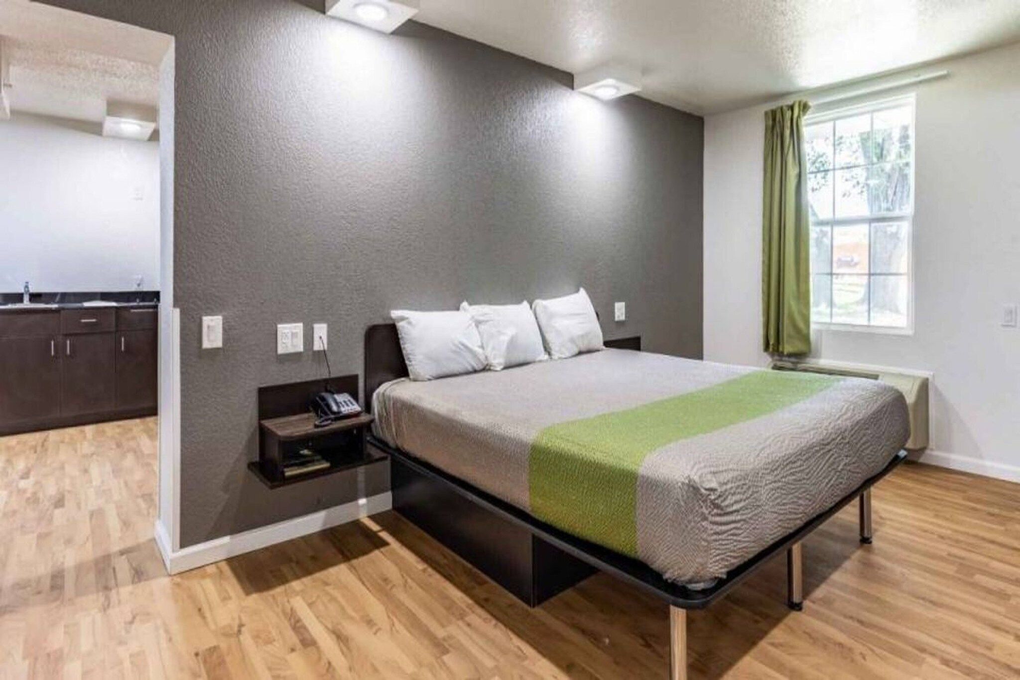 A bedroom with a bed, bedside table, and a window with curtains.
