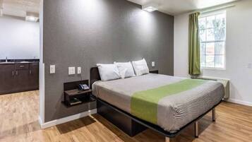 A bedroom with a bed, bedside table, and a window with curtains.