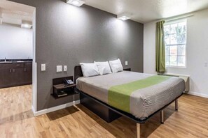 Un dormitorio con cama, mesita de noche y ventana con cortinas.