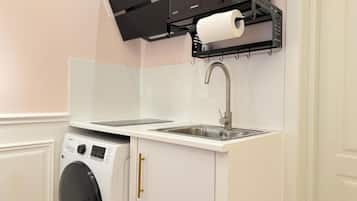 A compact kitchen with a built-in washing machine, a sink, and a microwave.