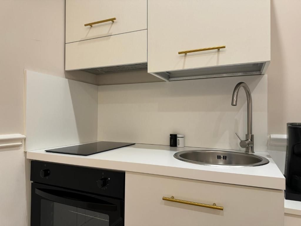 A modern kitchen with white cabinetry, a stainless steel sink, and a black dishwasher.