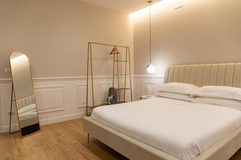 Une chambre à coucher avec un lit, une table de chevet, une lampe, un miroir et une échelle appuyée contre le mur.