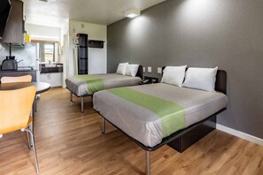 Ein Zimmer mit zwei Betten, einer kleinen Küchenzeile und einem Essbereich.