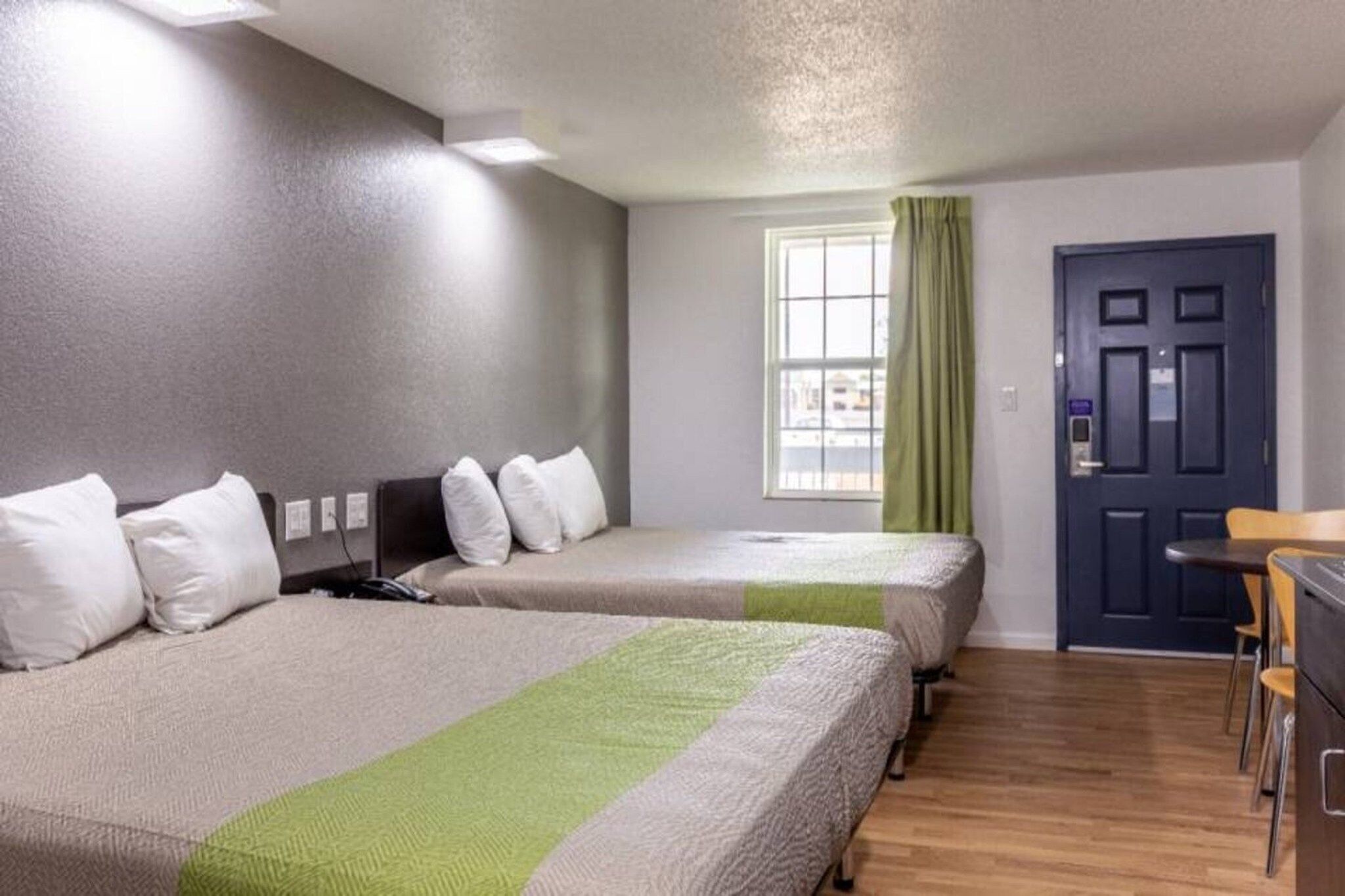 A hotel room with two beds, a desk, and a window with curtains.