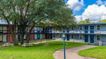 Un edificio de varios pisos con un patio central, un árbol y una mesa de picnic.