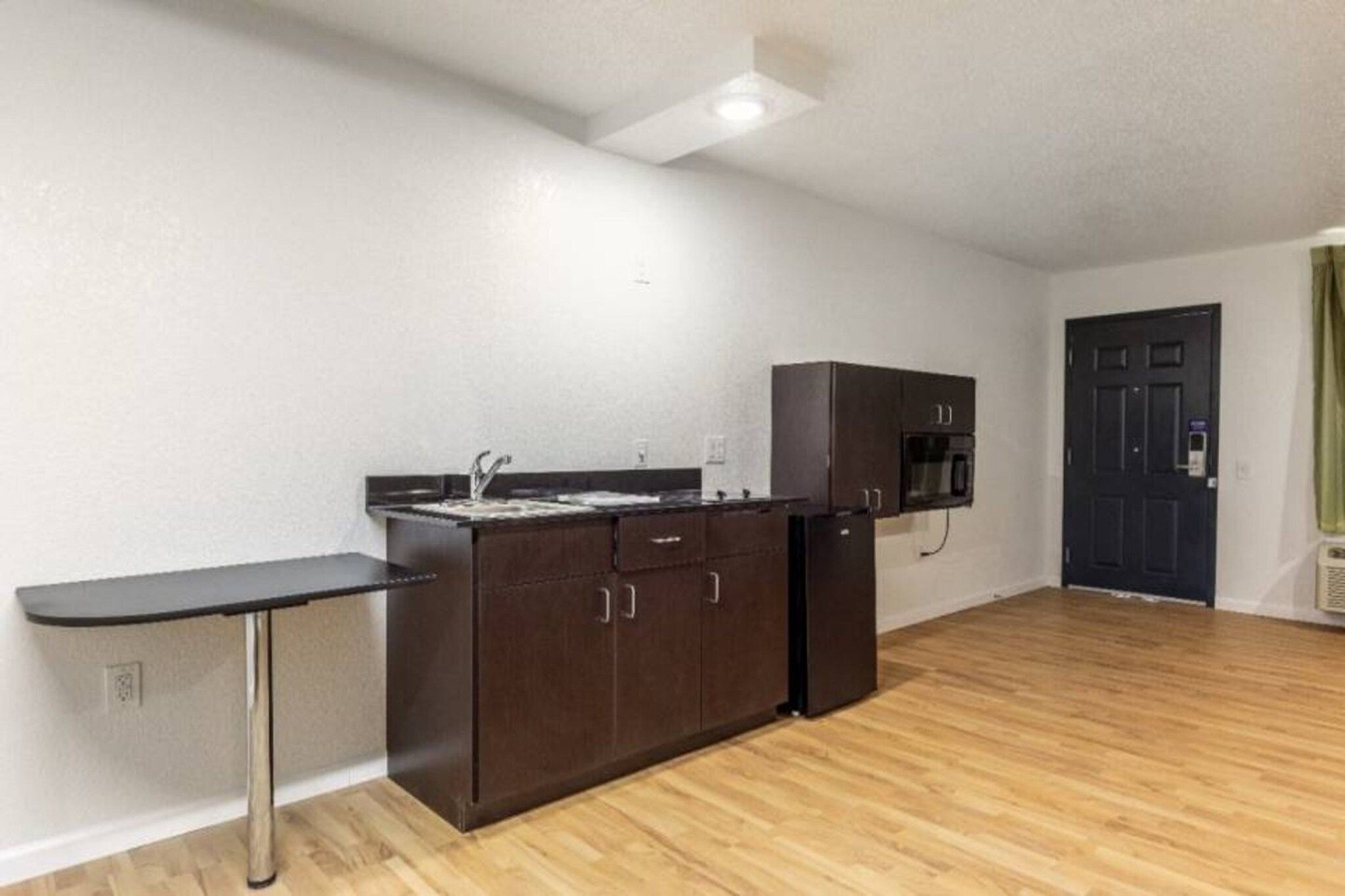 A compact kitchen with a sink, cabinets, and a microwave.