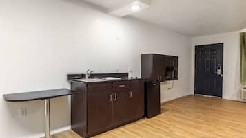 A compact kitchen with a sink, cabinets, and a microwave.