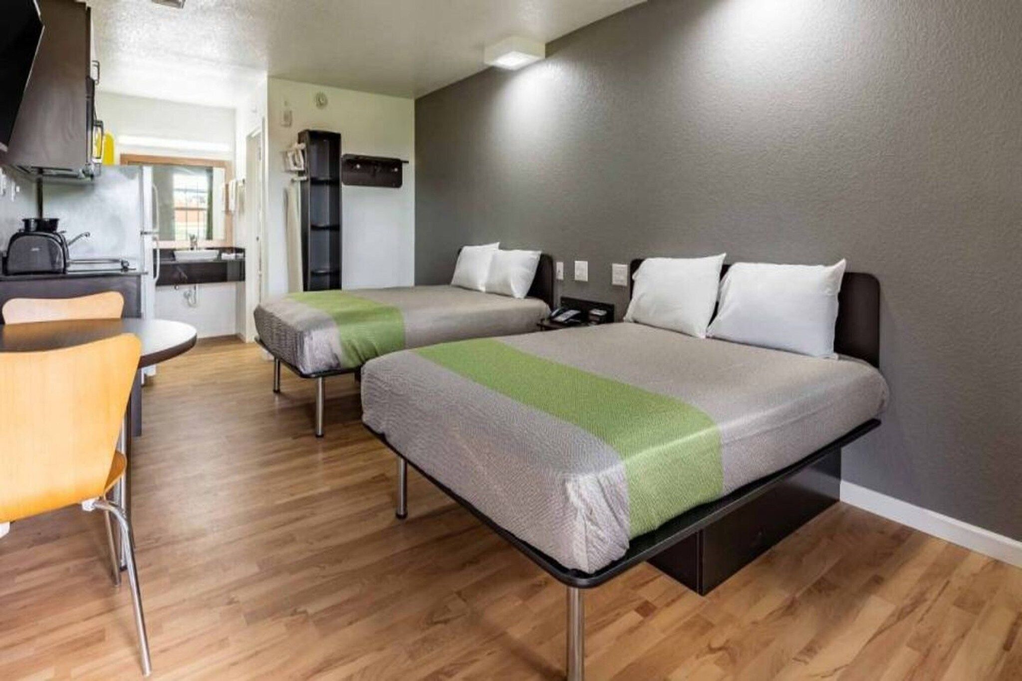Une chambre avec deux lits, une petite kitchenette et un coin repas.